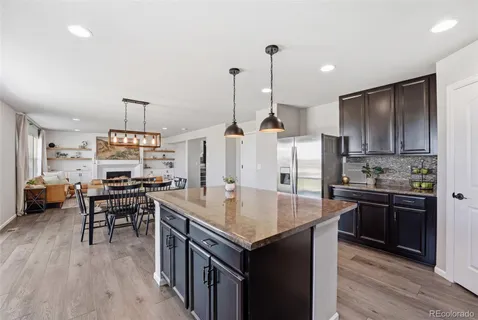 a kitchen with stainless steel appliances granite countertop a stove refrigerator and chairs