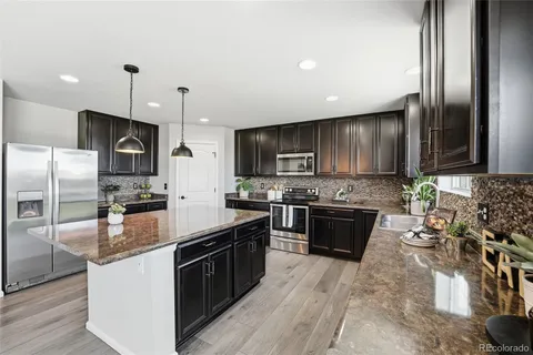 a large kitchen with stainless steel appliances granite countertop a stove a sink and a refrigerator