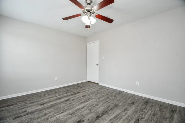 an empty room with wooden floor ceiling fan and windows