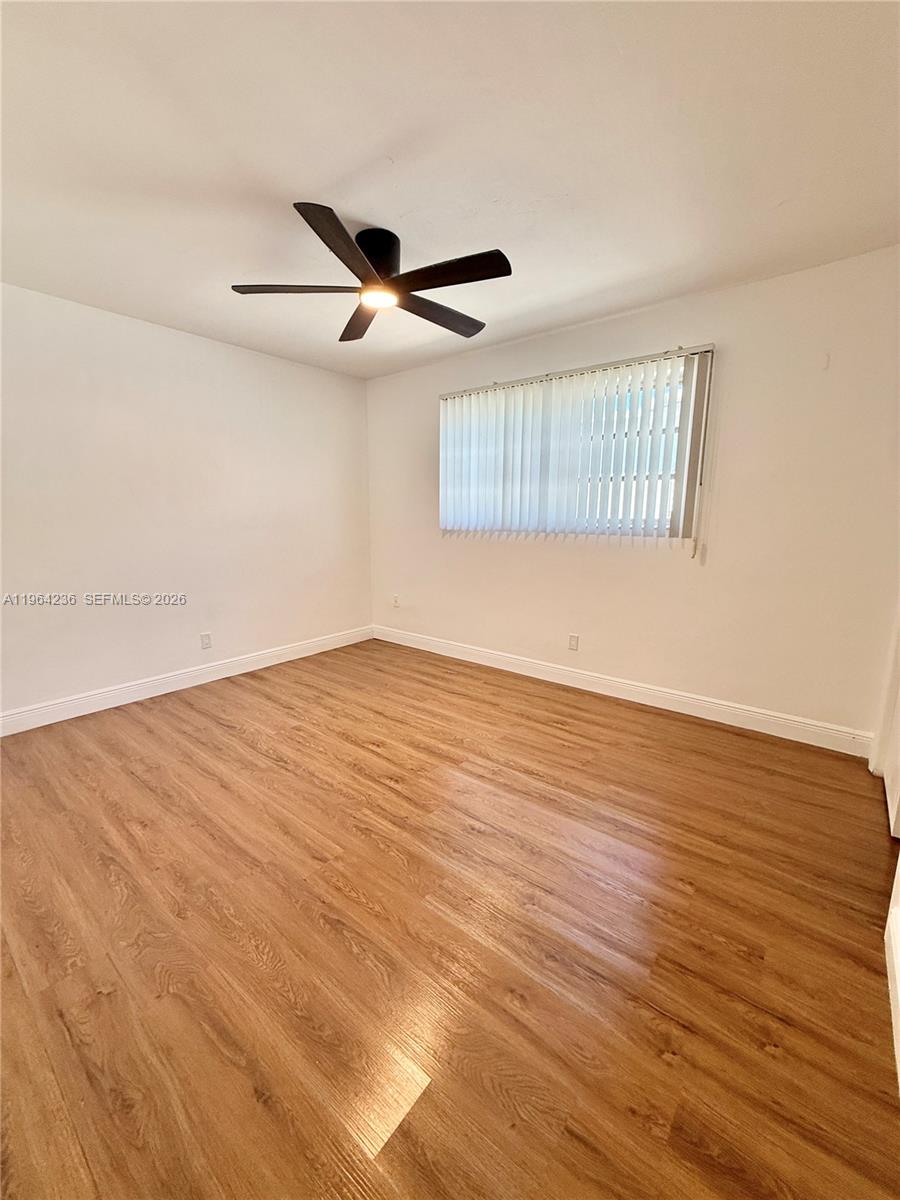 4917 West Park Road Hollywood, FL 33021 - Photo 16 of 25 an empty room with wooden floor ceiling fan and windows