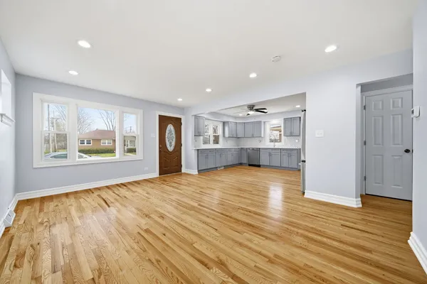 a kitchen with granite countertop a refrigerator oven a sink dishwasher and white cabinets with wooden floor