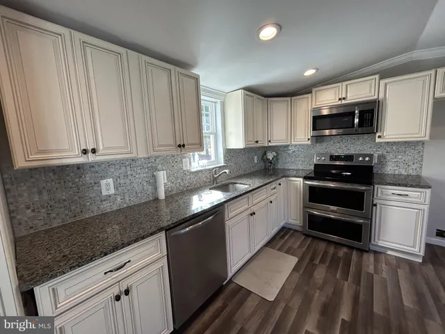 a kitchen with stainless steel appliances granite countertop a stove a sink and a microwave