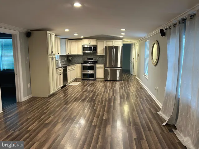 a open kitchen with kitchen island a refrigerator stove microwave and cabinets