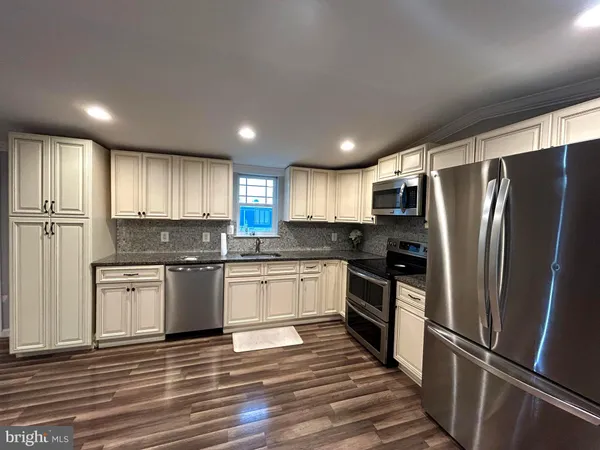 a kitchen with granite countertop stainless steel appliances a refrigerator cabinets and wooden floor