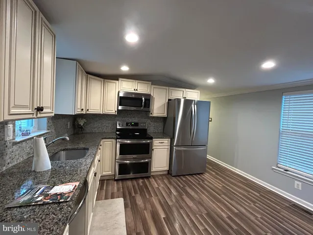a kitchen with granite countertop a refrigerator and a stove top oven