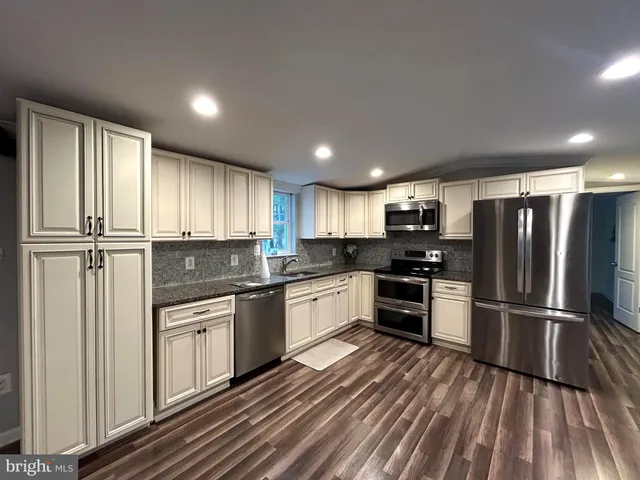 a kitchen with stainless steel appliances granite countertop a refrigerator and a stove top oven