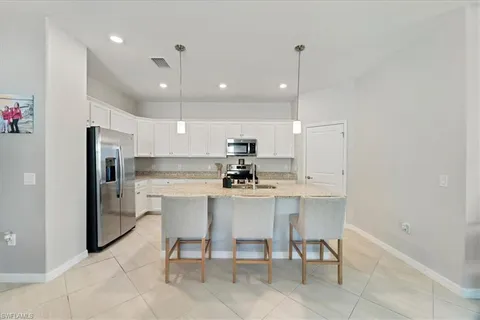 a kitchen with a sink a refrigerator and chairs