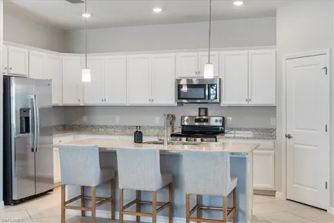 a kitchen with stainless steel appliances granite countertop a sink a stove a refrigerator and white cabinets with wooden floor