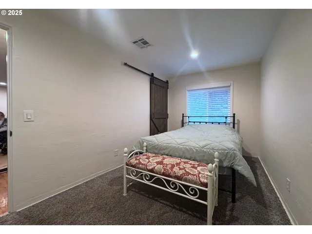 a bed sitting in a spacious bedroom next to a larger window