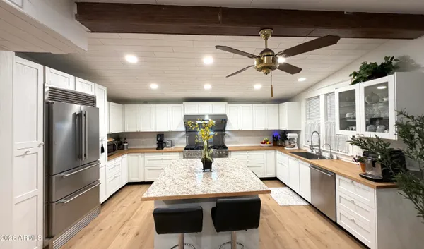 a kitchen with stainless steel appliances kitchen island granite countertop a stove refrigerator and cabinets