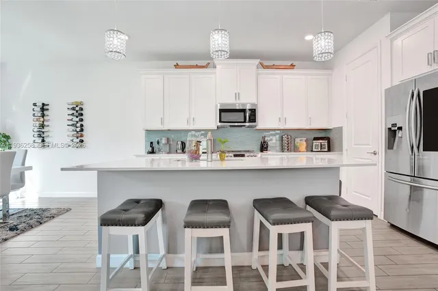 a kitchen with stainless steel appliances a dining table chairs sink and cabinets