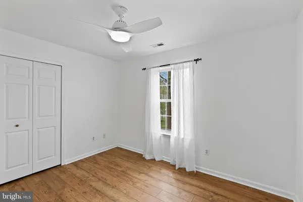 an empty room with wooden floor cabinet and windows