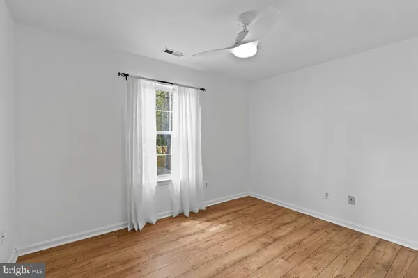 an empty room with wooden floor fan and window