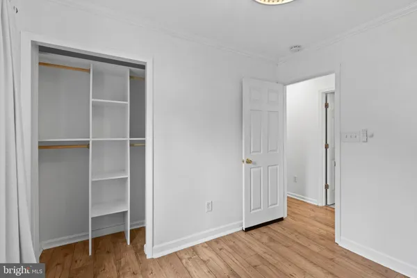 a view of an empty room with wooden floor and closet