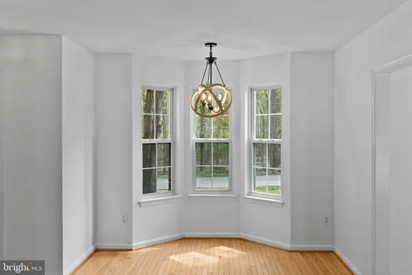 a view of an empty room with window and wooden floor