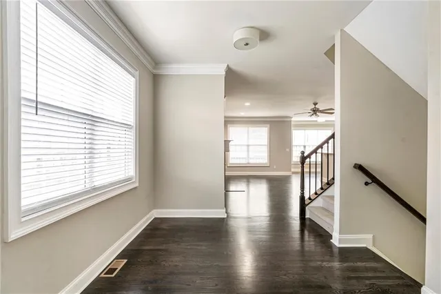 a view of empty room with wooden floor and fan