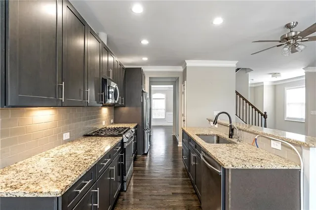 a kitchen with stainless steel appliances granite countertop a sink a stove top oven a counter space and cabinets