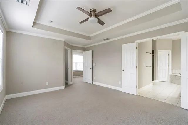 an empty room with chandelier fan and windows