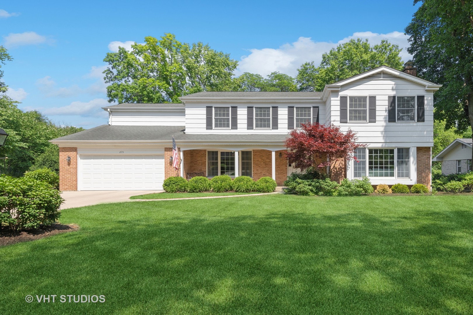 a front view of a house with a yard and trees