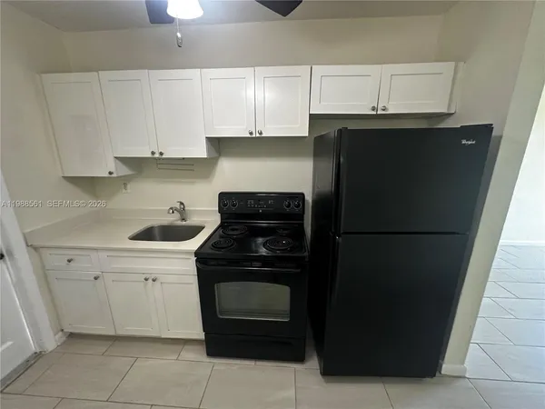 a view of a refrigerator in kitchen and an empty room
