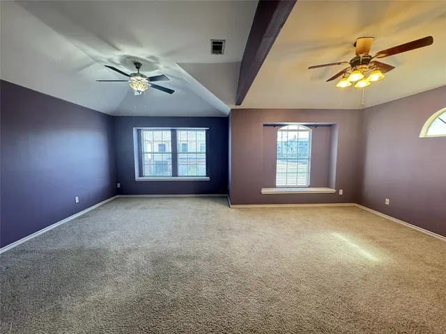 a view of an empty room with a ceiling fan and window