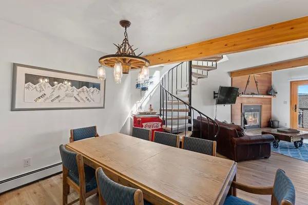 a dining room with wooden floor a chandelier a wooden table and chairs