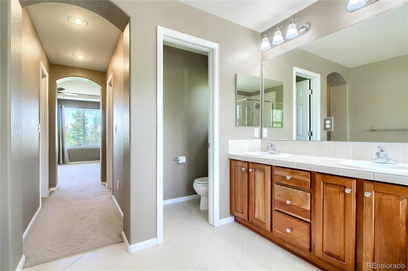 2705 Middlebury Drive Highlands Ranch, CO 80126 - Photo 28 of 40 a spacious bathroom with a double vanity sink a toilet and a large mirror