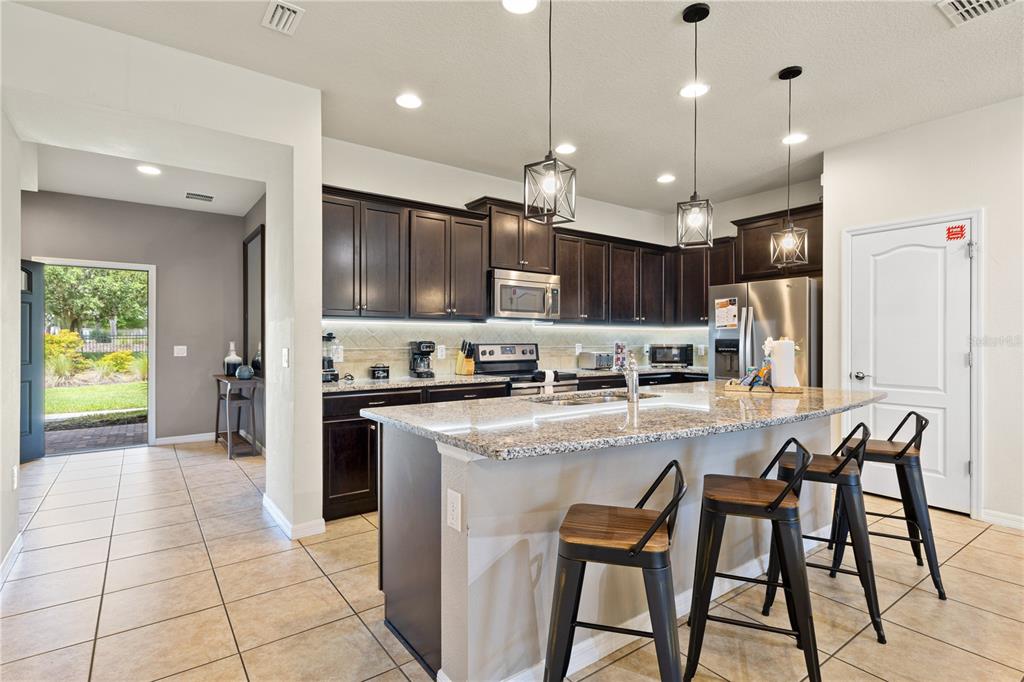 1905 Majorca Drive Kissimmee, FL 34747 - Photo 40 of 59 a kitchen with stainless steel appliances granite countertop a stove top oven a refrigerator a sink and a oven