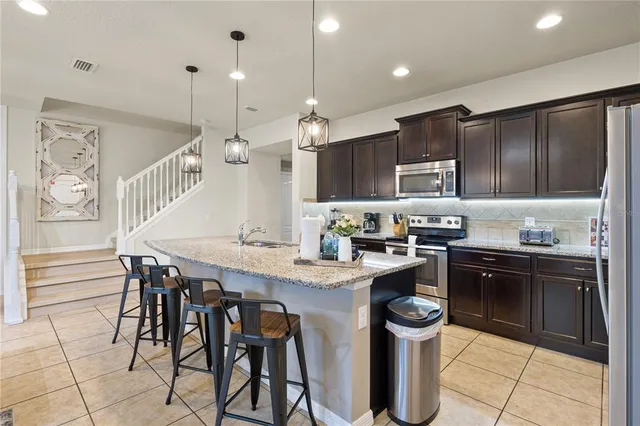 a living room with furniture a kitchen view and a refrigerator