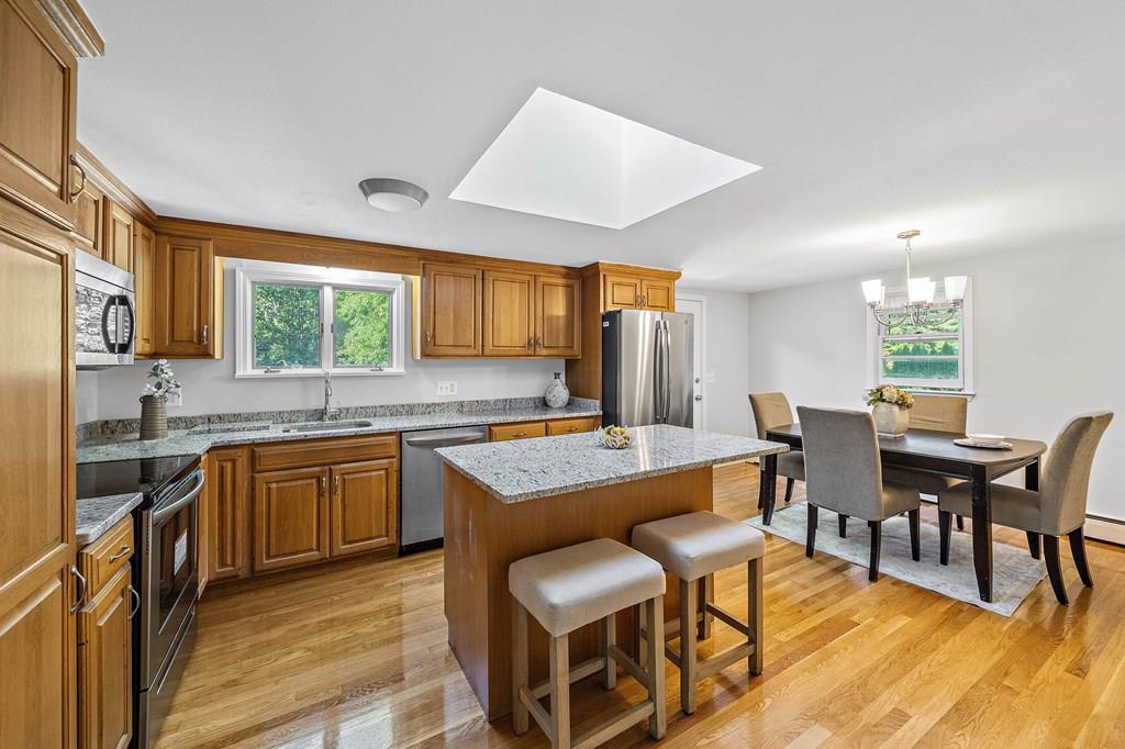 1075 Glebe Street Taunton, MA 02780 - Photo 2 of 31 a kitchen with granite countertop a stove a sink a dining table and chairs