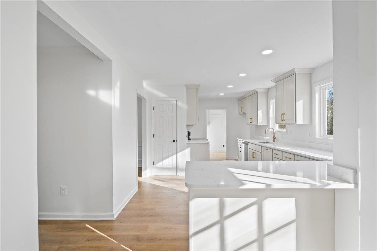 1676 Miller Farms Road Germantown, TN 38138 - Photo 11 of 37 Open-concept kitchen featuring light wood-finish flooring, white cabinetry with gold-tone hardware, white countertops, recessed lighting, and a white subway tile backsplash