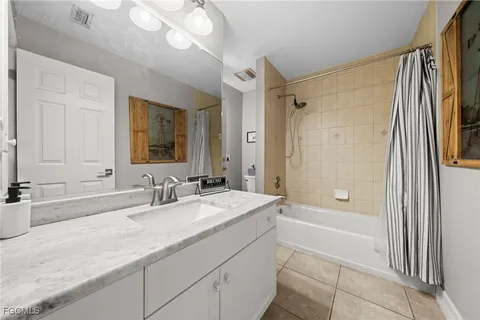 a bathroom with a granite countertop sink a mirror a bathtub and shower