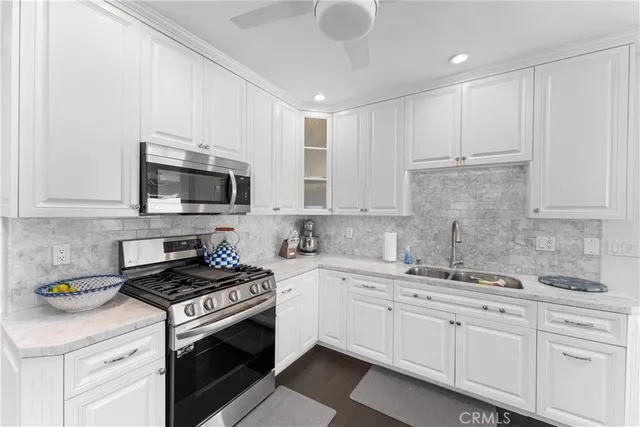 a kitchen with granite countertop white cabinets stainless steel appliances and a sink