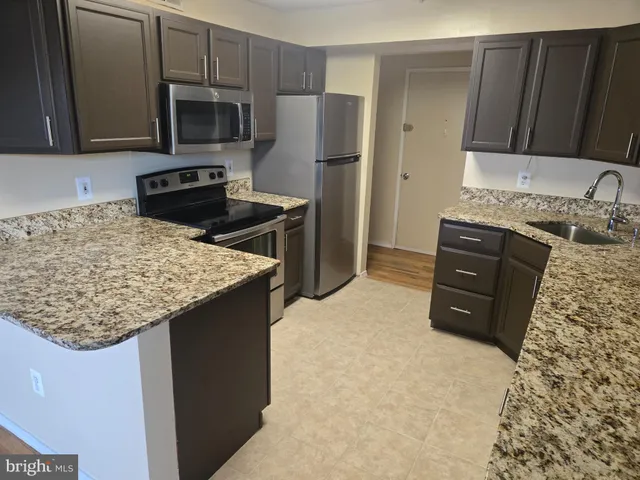 a kitchen with granite countertop kitchen island stainless steel appliances a sink table and chairs