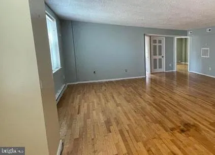 a view of empty room with window and wooden floor