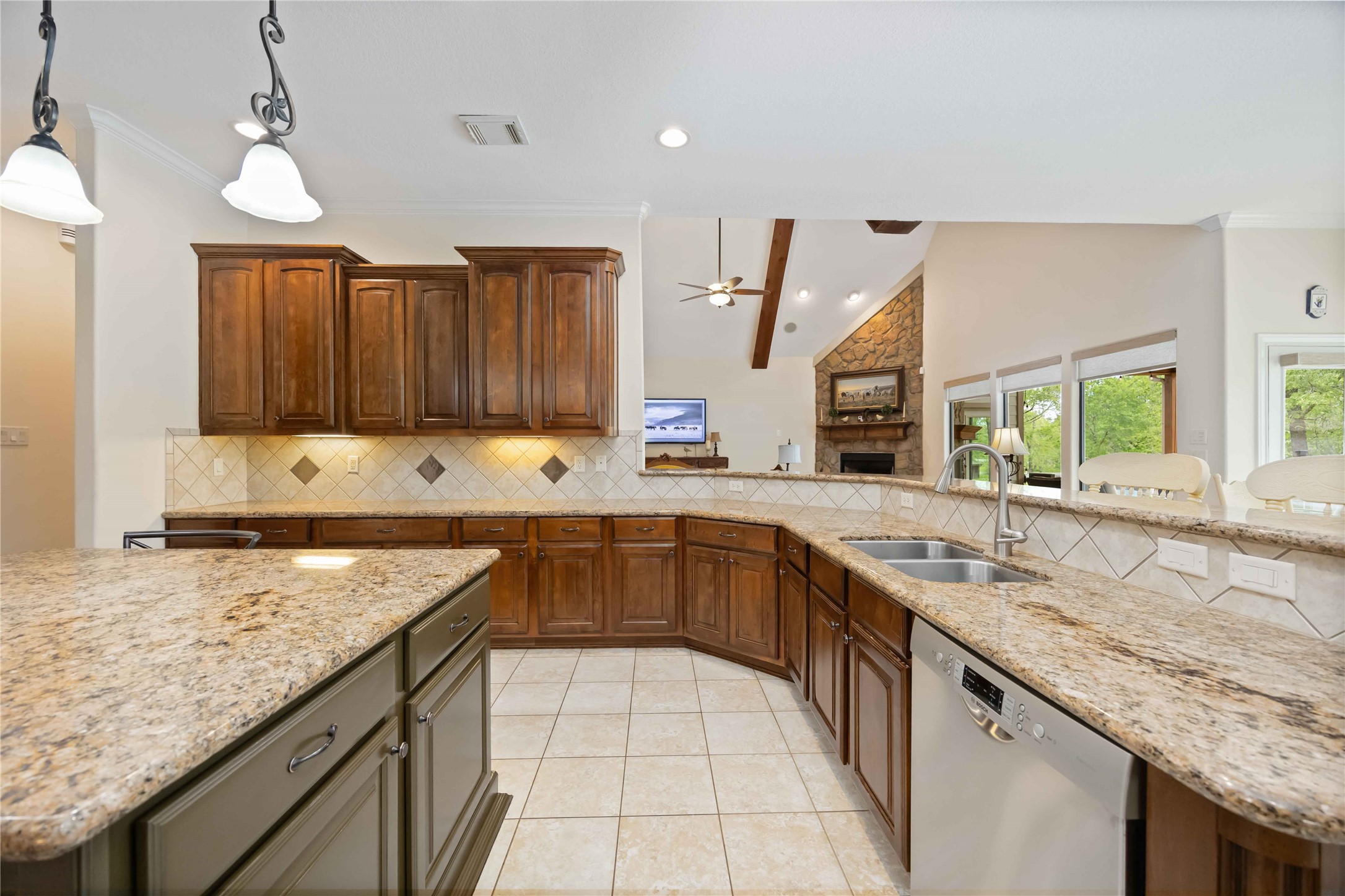 1809 St Beulah Chapel Road Montgomery, TX 77316 - Photo 12 of 50 This spacious kitchen features granite countertops, a large island, and wooden cabinetry. It opens to a living area with a stone fireplace and large windows for abundant natural light.