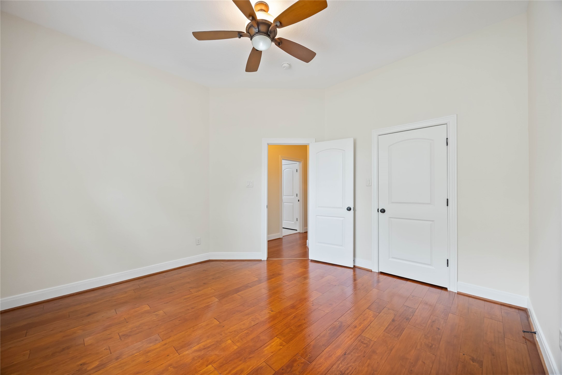1809 St Beulah Chapel Road Montgomery, TX 77316 - Photo 18 of 50 Bright room with hardwood flooring, neutral walls, and a ceiling fan. It features two white doors, one leading to a hallway.