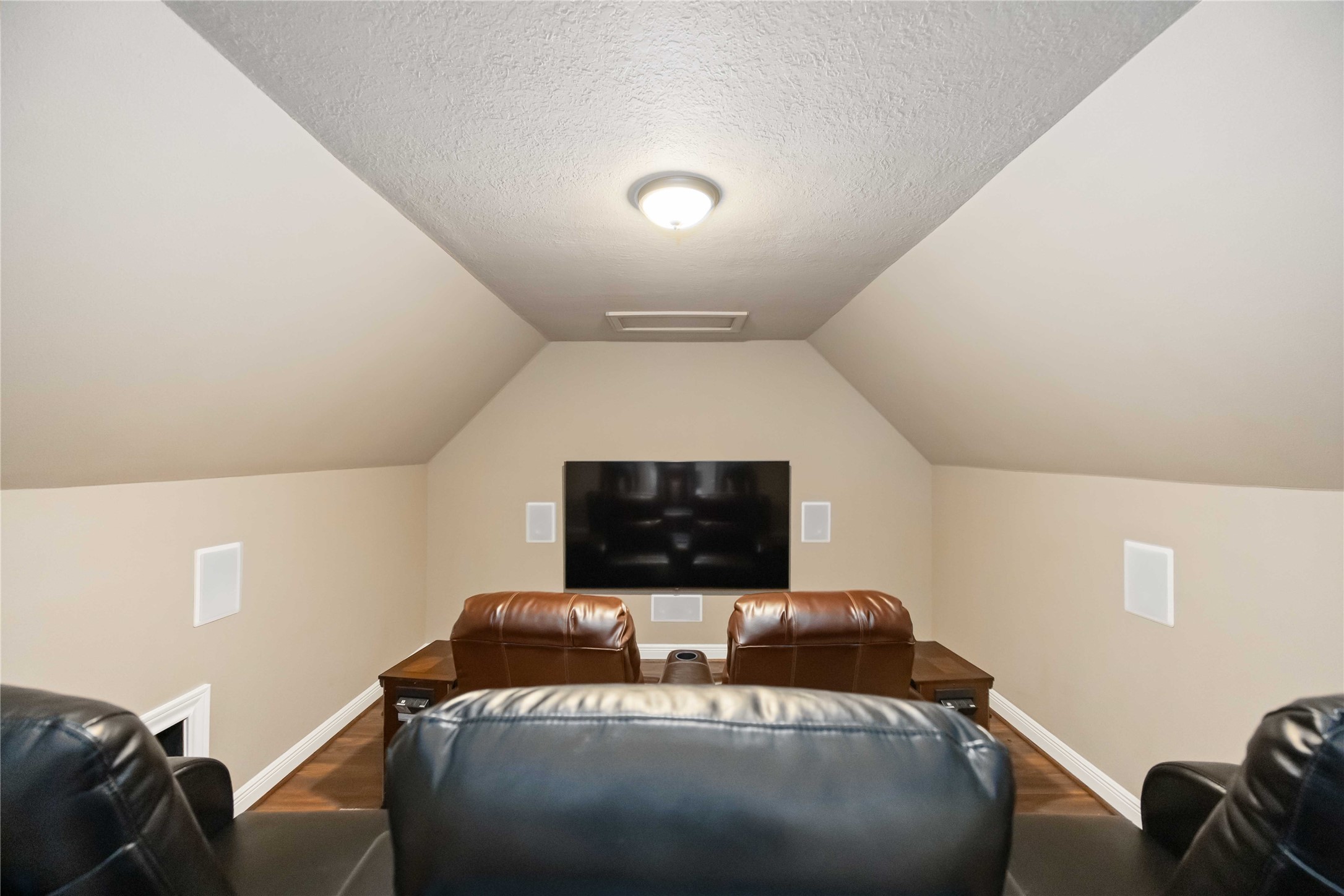 1809 St Beulah Chapel Road Montgomery, TX 77316 - Photo 30 of 50 Cozy home theater room with sloped ceilings, featuring comfortable leather seating and a wall-mounted TV for an immersive entertainment experience.