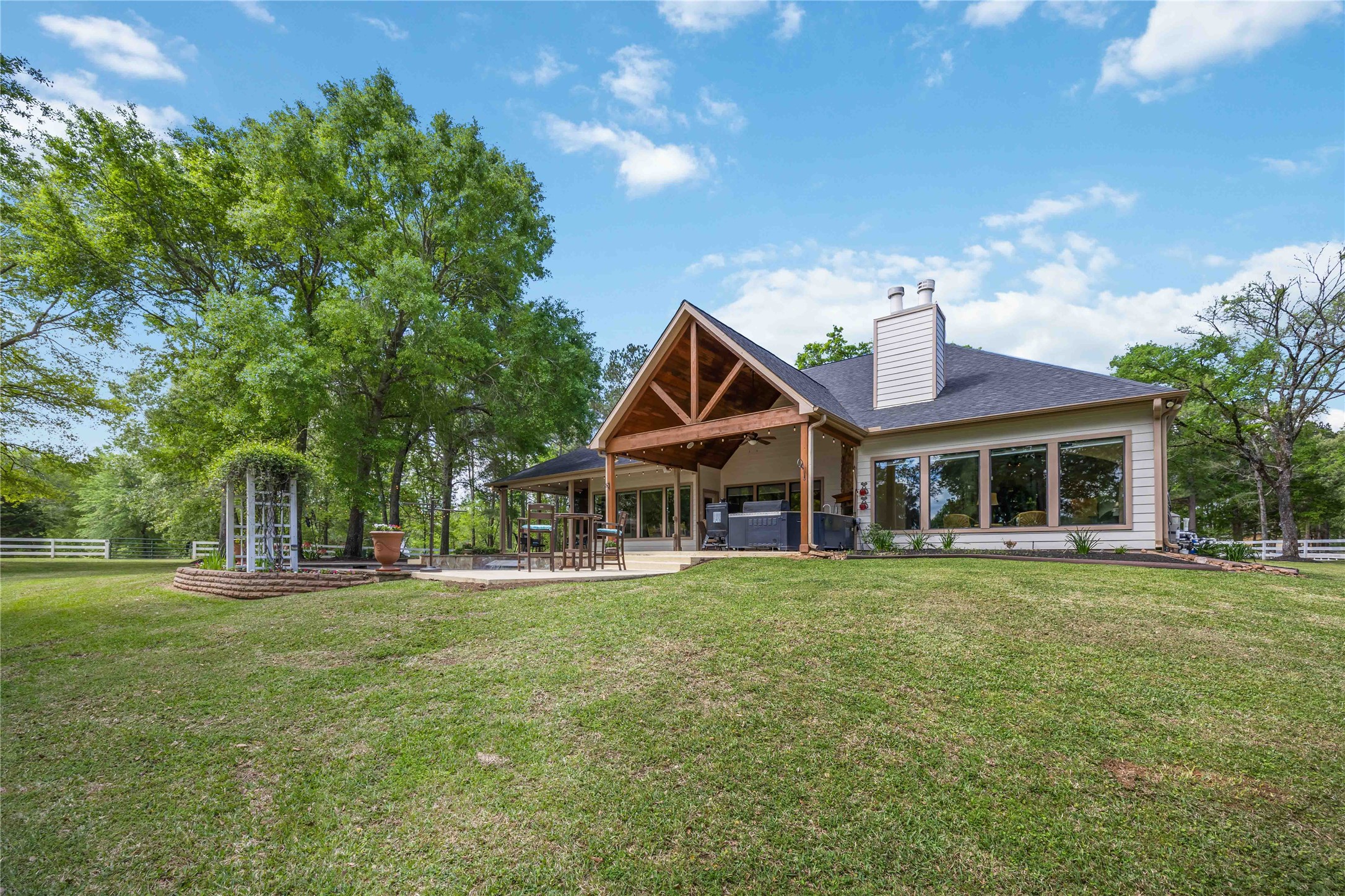 1809 St Beulah Chapel Road Montgomery, TX 77316 - Photo 39 of 50 This beautiful home features a spacious backyard with lush greenery and a covered outdoor patio. Large windows provide plenty of natural light, and the architectural design includes a charming gabled roof, perfect for enjoying serene views and outdoor gatherings.