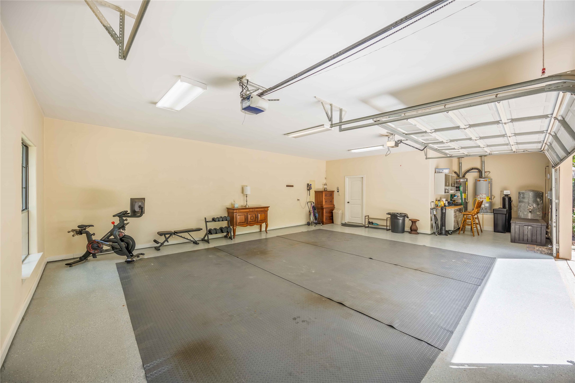 1809 St Beulah Chapel Road Montgomery, TX 77316 - Photo 43 of 50 Spacious and well-lit garage with ample room for vehicles and storage. Features include a workout area with exercise equipment, neatly organized tools, and utility systems tucked in the corner. Ideal for multi-purpose use.