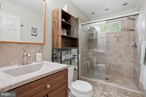 a bathroom with a granite countertop sink a toilet a mirror and shower