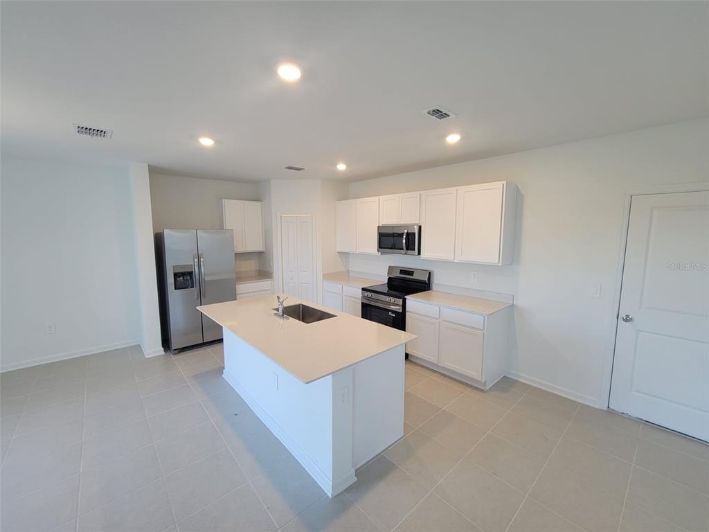 3147 Totem Road Eagle Lake, FL 33839 - Photo 6 of 18 a large kitchen with stainless steel appliances a sink a refrigerator and white cabinets
