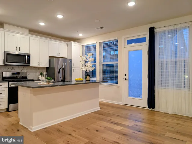 a view of kitchen with stainless steel appliances granite countertop a refrigerator and a stove top oven