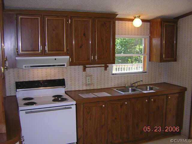 174 Rubermont Road Victoria, VA 23974 - Photo 3 of 4 a kitchen with granite countertop a sink a stove and wooden cabinets
