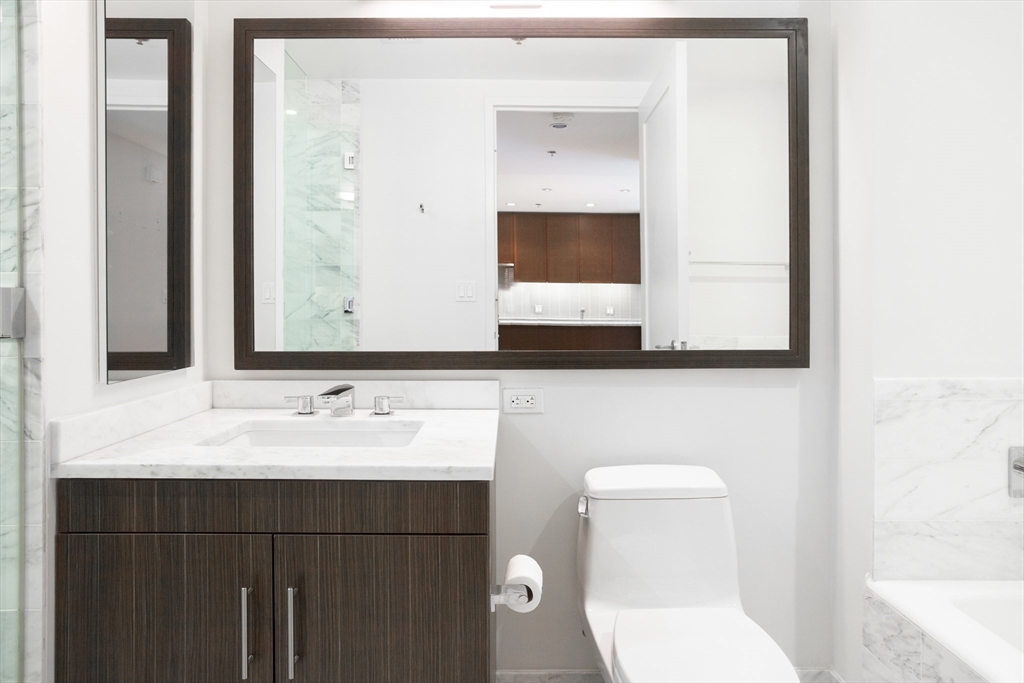 580 Washington Street, Unit 304 Boston, MA 02111 - Photo 17 of 18 a bathroom with a toilet sink and mirror
