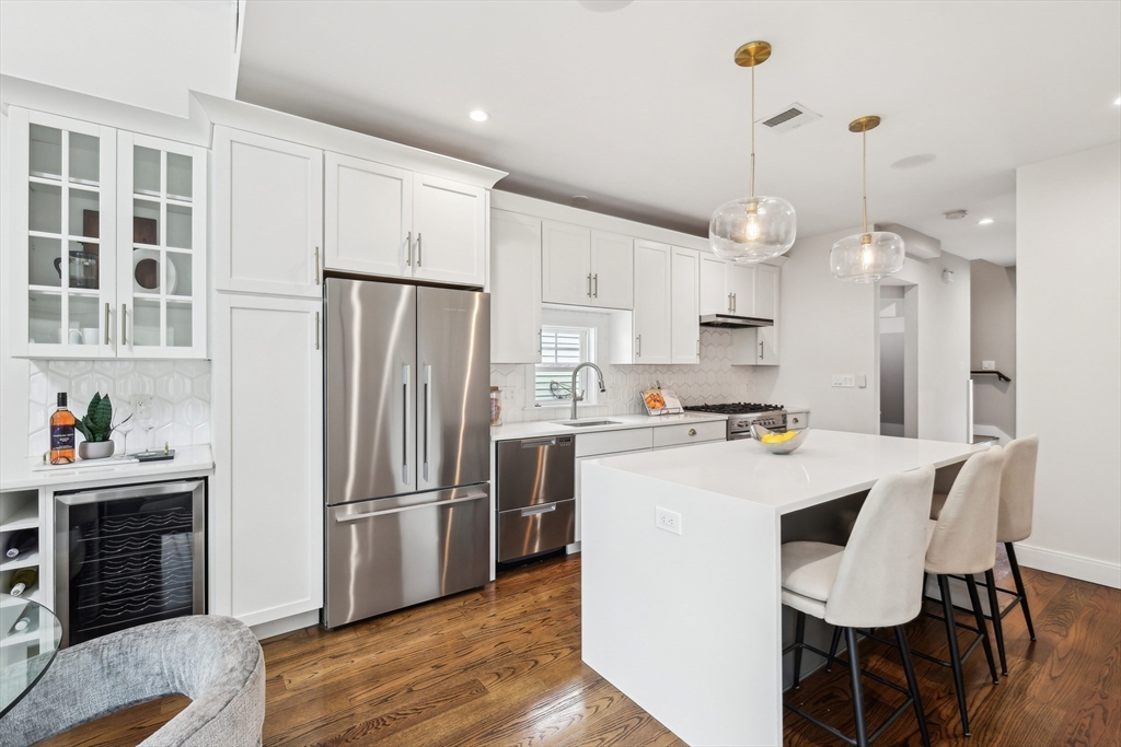 26 Robinson Street, Unit 26 Somerville, MA 02145 - Photo 6 of 29 a kitchen with kitchen island a refrigerator a stove a sink and a dining table with wooden floor