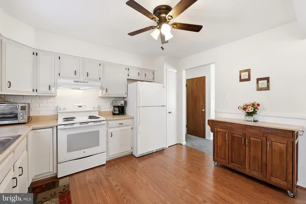 a kitchen with stainless steel appliances white cabinets and wooden floor