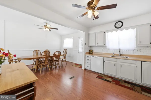 a open kitchen with stainless steel appliances granite countertop a stove a sink a dining table and chairs with wooden floor