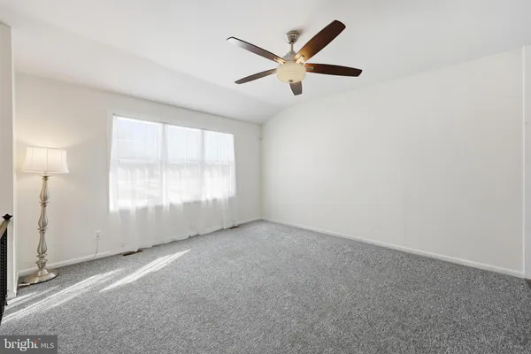 an empty room with a ceiling fan and windows