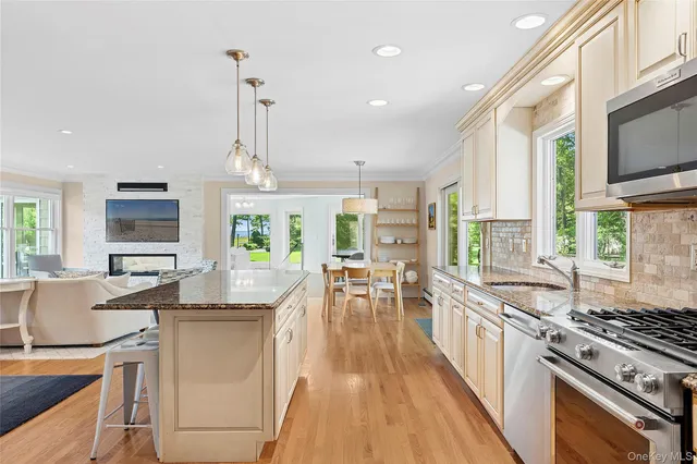 a kitchen with stainless steel appliances a stove a sink a oven a dining table and chairs with wooden floor